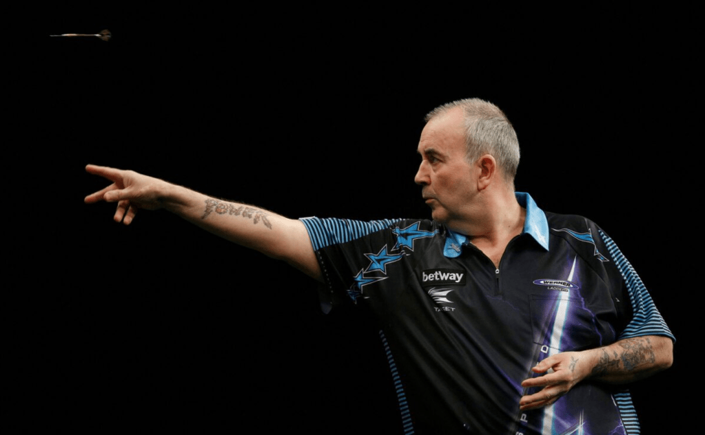 A side profile image of Phil 'The Power' Taylor. Phil is midway through his release, and the dart is located in the top left-hand corner.