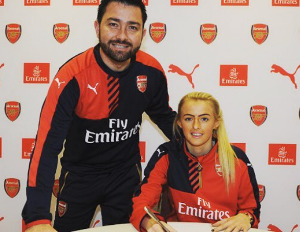 This photo shows Chloe Kelly signing her first professional contract at Arsenal. She has the pen in her right hand, whilst a club representative stands beside her.